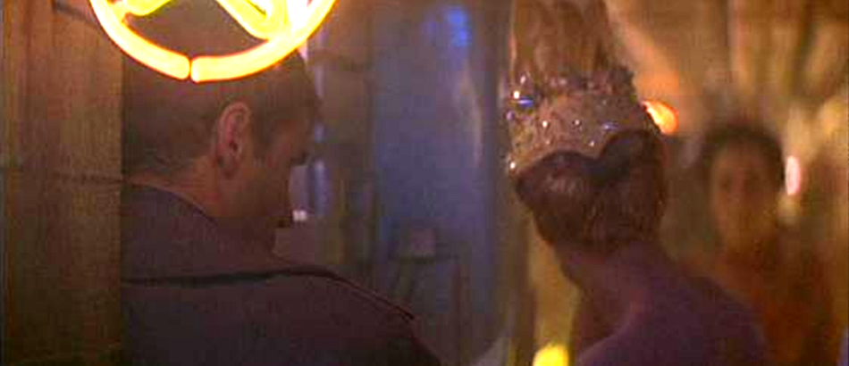 Figure 27: Blade Runner. Deckard leans against a neon star. The busy backstage is an allusion to Losey’s films. Note the girl in the chicken hat as in Time without Pity and (a bit out of focus) the girl in the background with the cumbersome headdress not too dissimilar to the one in Monsieur Klein.